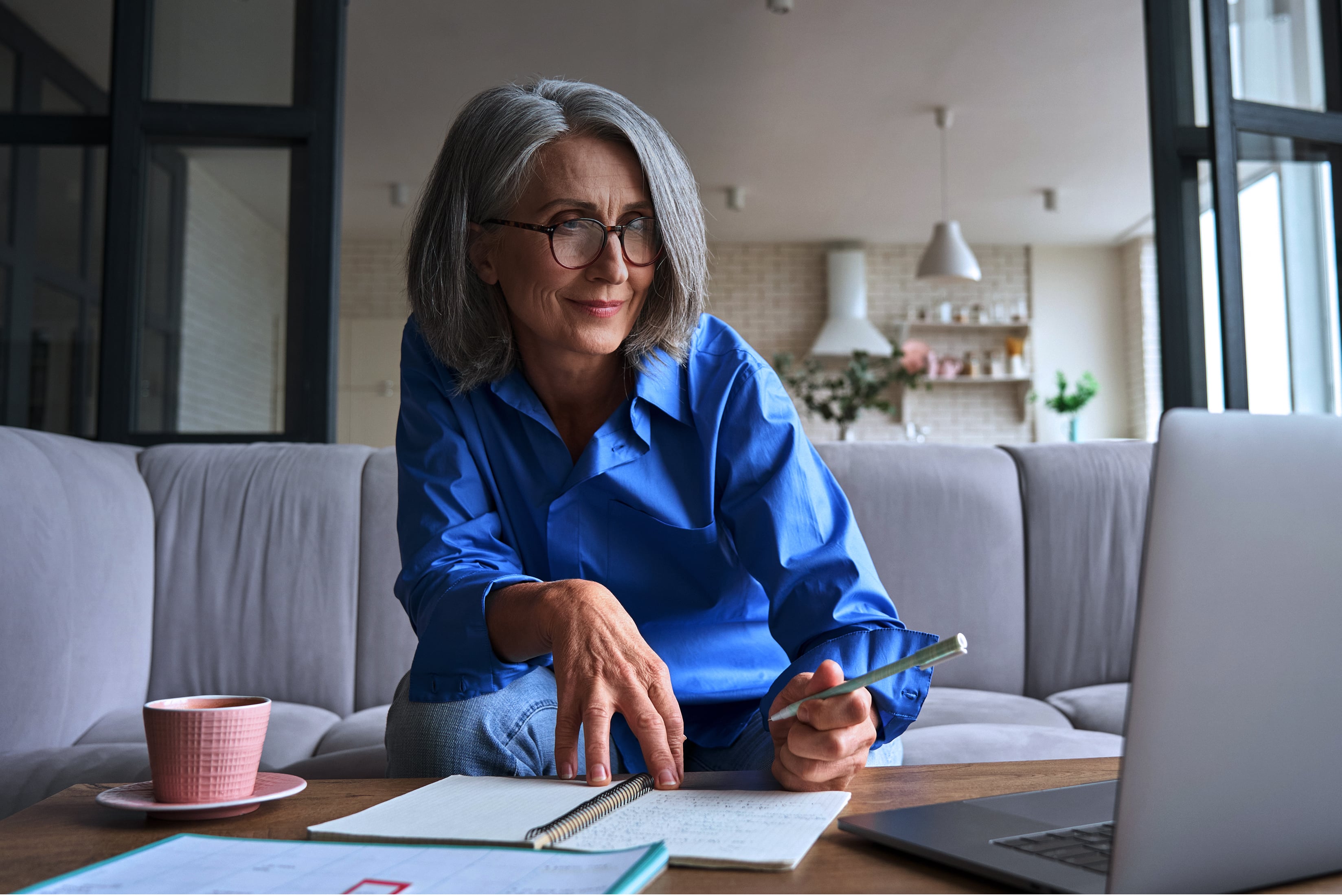 Middle-aged woman sitting on couch, working on laptop